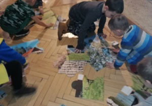 Grupa chłopców układa puzzle.